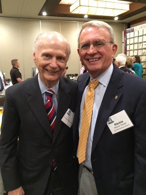 Two men in suits and ties posing for a picture.